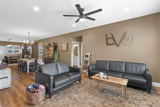 living room featuring hardwood / wood-style flooring and ceiling fan with notable chandelier