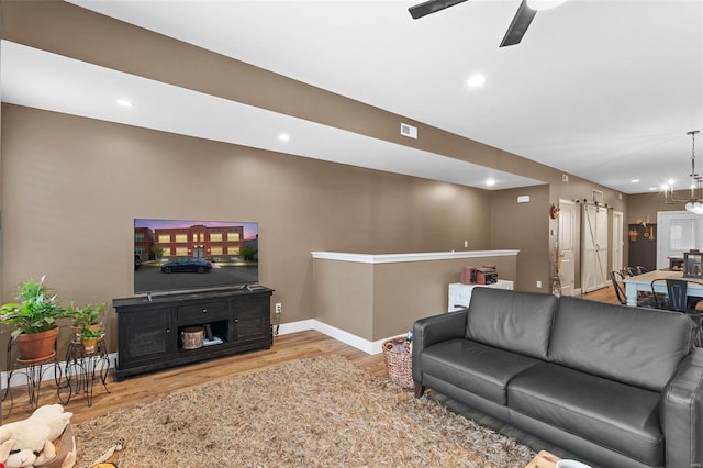 living room featuring hardwood / wood-style flooring and ceiling fan with notable chandelier