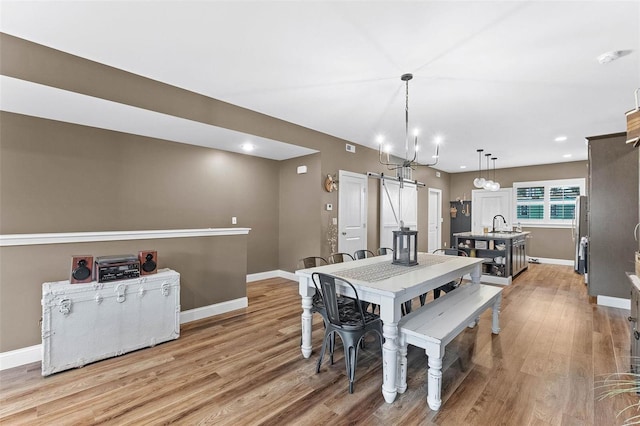 dining space with an inviting chandelier, hardwood / wood-style floors, and a barn door