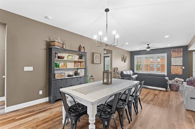 dining room featuring light hardwood / wood-style flooring and ceiling fan with notable chandelier