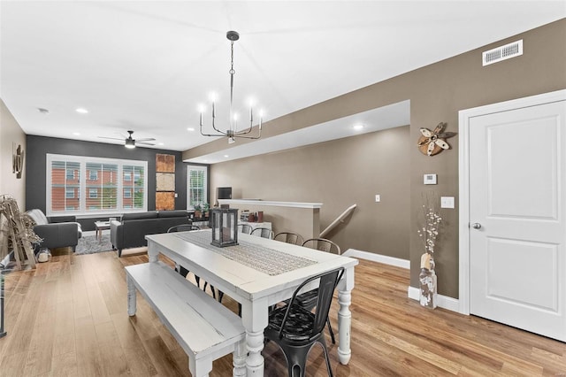 dining room with light hardwood / wood-style flooring and ceiling fan with notable chandelier