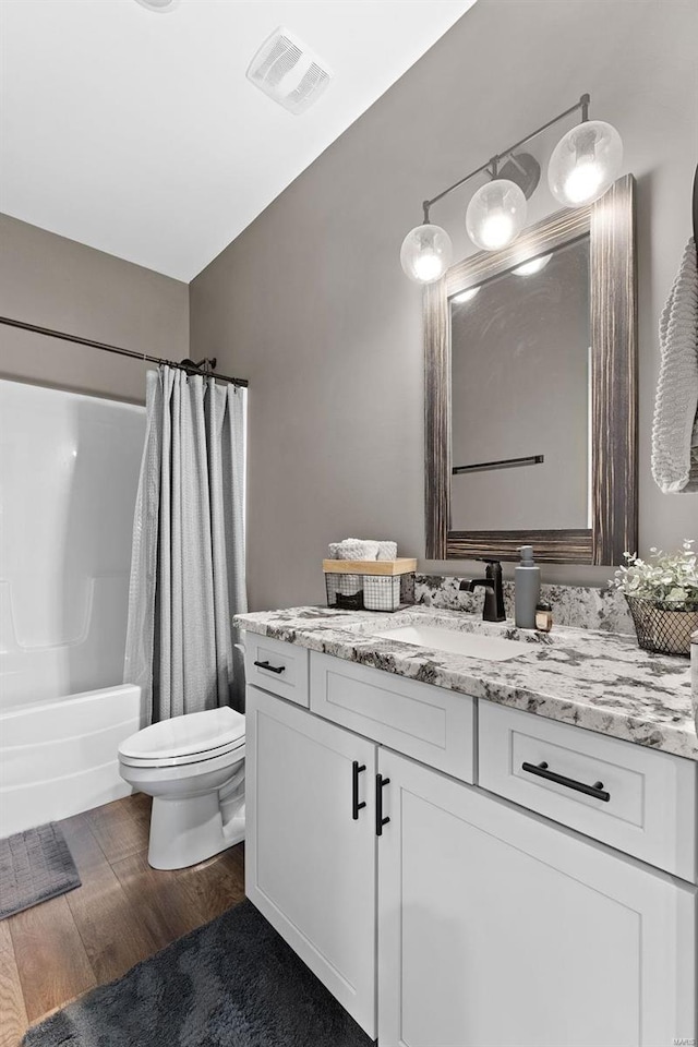 full bathroom with toilet, hardwood / wood-style floors, shower / bath combo with shower curtain, and vanity