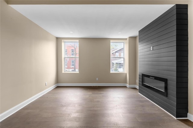 unfurnished living room featuring wood-type flooring and a large fireplace