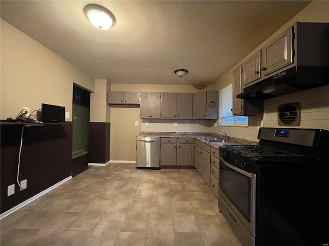 kitchen featuring gray cabinets, stainless steel appliances, and dark stone counters