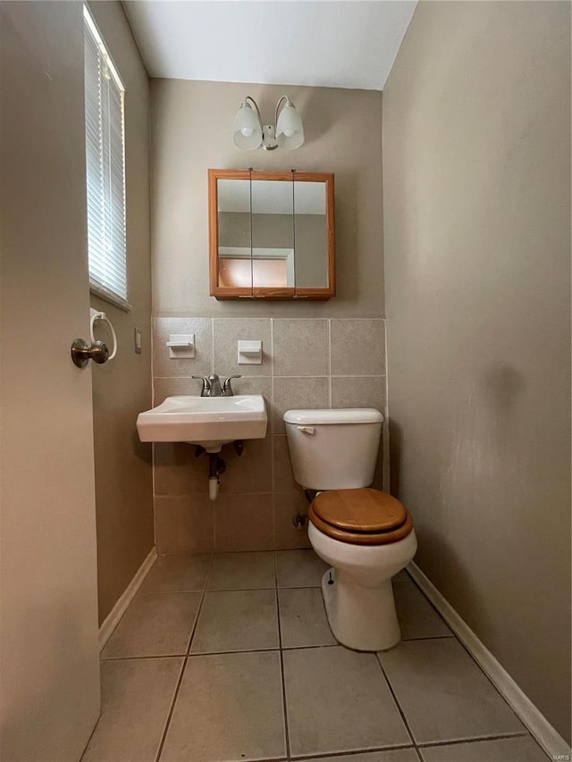 bathroom with tile walls, tile patterned floors, sink, and toilet