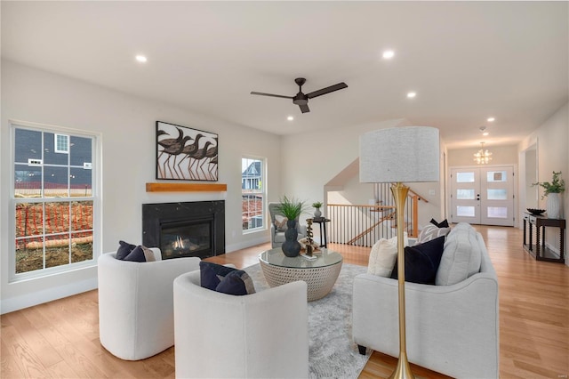 living room with ceiling fan with notable chandelier and light wood-type flooring