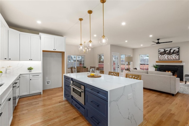 kitchen featuring decorative light fixtures, stainless steel oven, white cabinets, and a center island