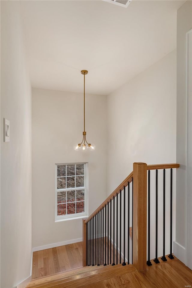 stairway with wood-type flooring and a chandelier