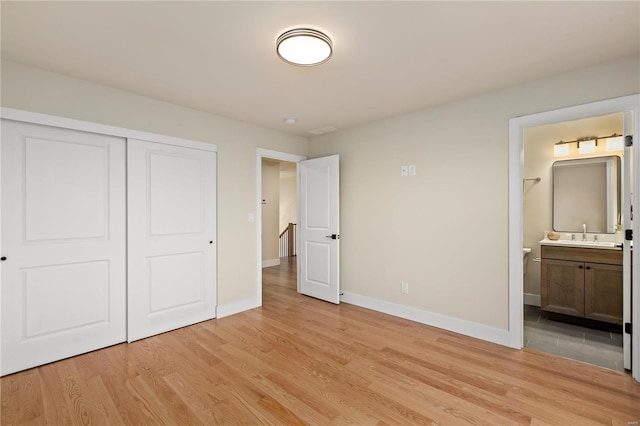 unfurnished bedroom with ensuite bathroom, sink, light hardwood / wood-style floors, and a closet