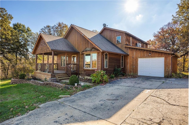 view of front of house with a porch, a garage, and a front lawn