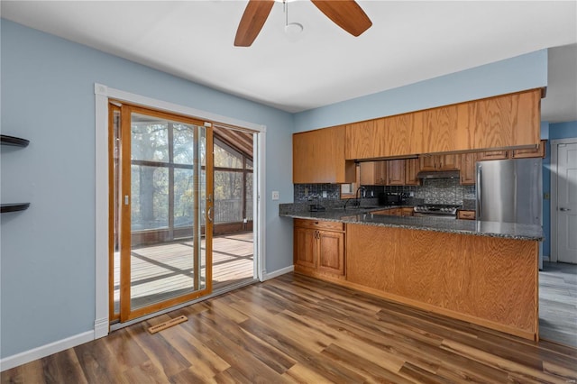 kitchen featuring kitchen peninsula, decorative backsplash, stainless steel appliances, and dark hardwood / wood-style floors