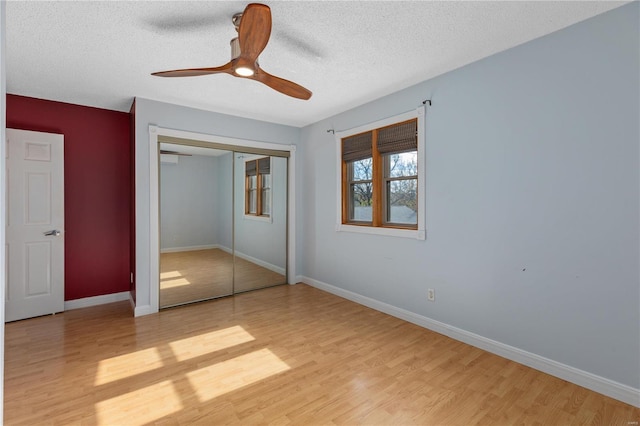 unfurnished bedroom with a closet, a textured ceiling, light hardwood / wood-style floors, and ceiling fan