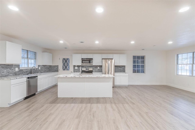 kitchen featuring white cabinetry, light wood-type flooring, stainless steel appliances, and a kitchen island