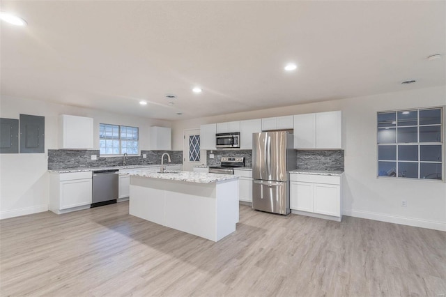 kitchen featuring white cabinetry, appliances with stainless steel finishes, an island with sink, and light stone counters