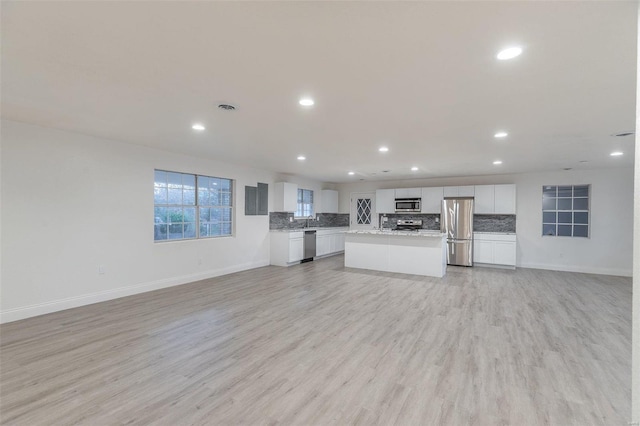 kitchen with tasteful backsplash, appliances with stainless steel finishes, a center island, and light hardwood / wood-style floors