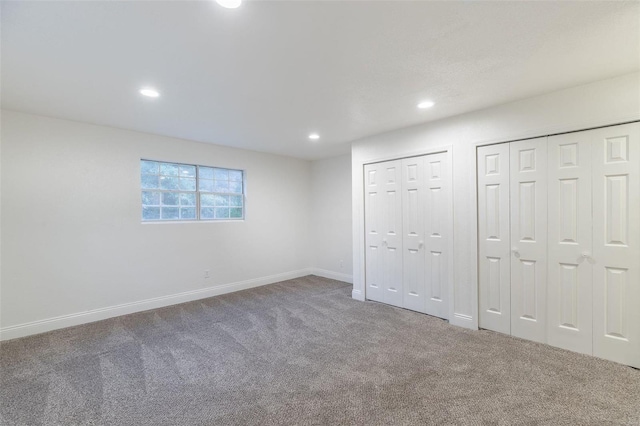 unfurnished bedroom featuring carpet flooring and two closets