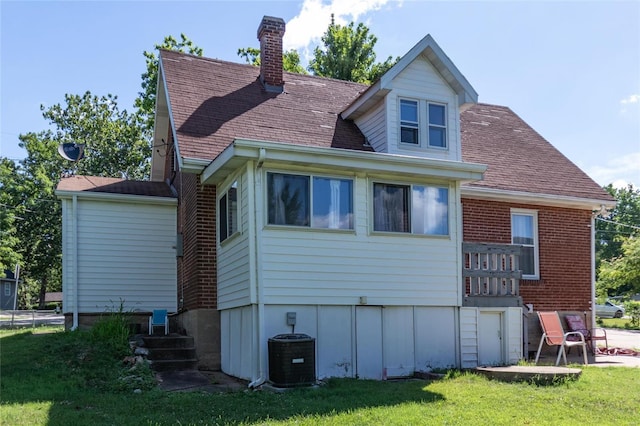 rear view of property featuring a lawn and central air condition unit