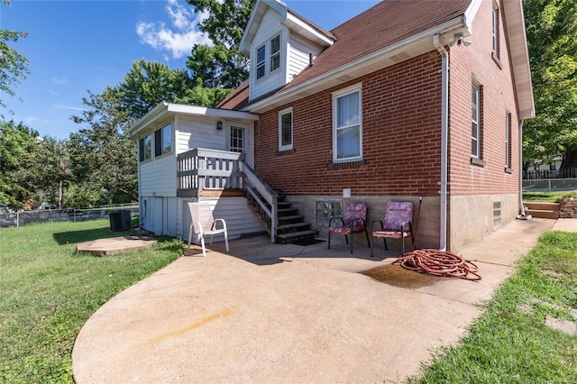 rear view of house featuring central AC unit, a patio area, and a lawn