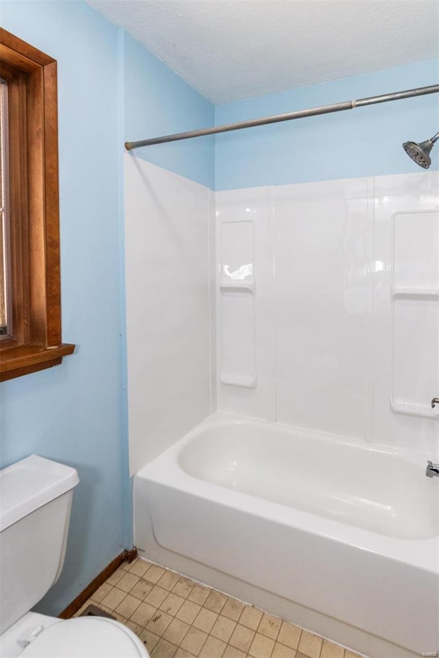 bathroom with shower / bathing tub combination, a textured ceiling, and toilet