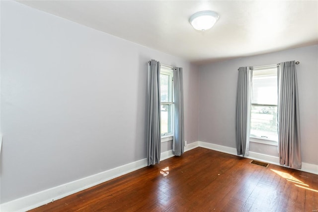 empty room with dark wood-type flooring and a wealth of natural light