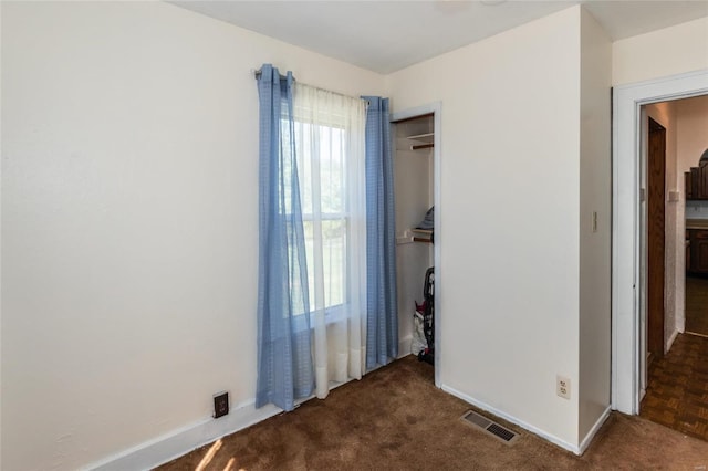 unfurnished bedroom featuring dark parquet floors and a closet