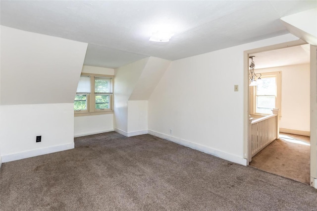 bonus room featuring vaulted ceiling, carpet floors, and an inviting chandelier