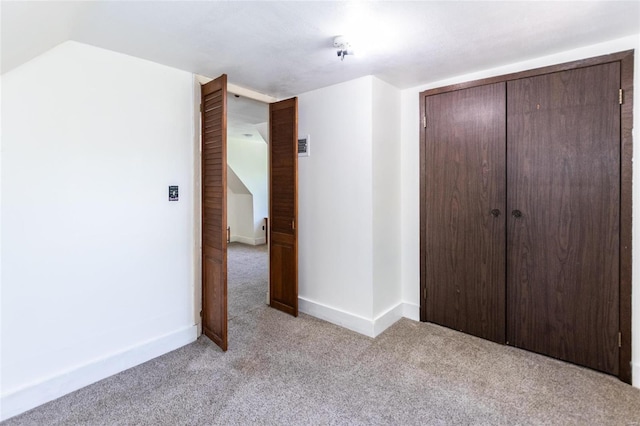 unfurnished bedroom featuring lofted ceiling, light carpet, and a closet