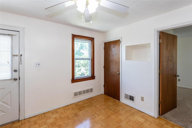 interior space featuring multiple windows, light parquet floors, and ceiling fan