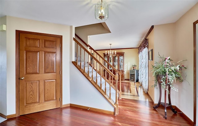 foyer entrance featuring hardwood / wood-style flooring, crown molding, and an inviting chandelier