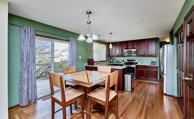 dining area with a chandelier, sink, and light hardwood / wood-style flooring