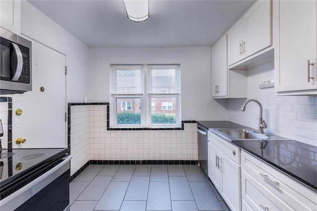 kitchen featuring tile walls, stainless steel appliances, dark tile patterned floors, white cabinetry, and sink