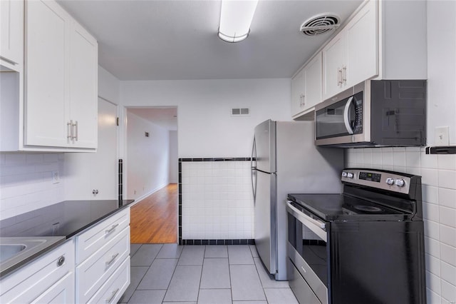 kitchen with white cabinets, light tile patterned floors, and appliances with stainless steel finishes