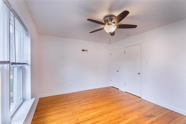 unfurnished room featuring a wealth of natural light, ceiling fan, and light wood-type flooring