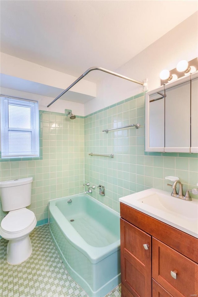 full bathroom with toilet, vanity, tiled shower / bath combo, and tile walls