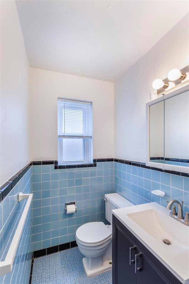 bathroom featuring toilet, vanity, tile walls, and tile patterned floors