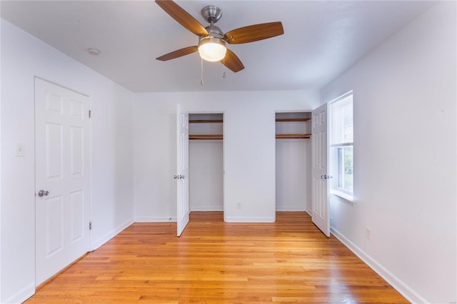 unfurnished bedroom with light hardwood / wood-style floors, ceiling fan, and two closets