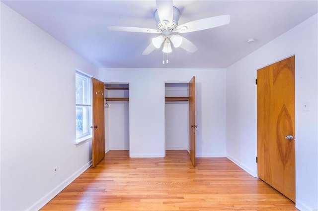 unfurnished bedroom with light wood-type flooring, two closets, and ceiling fan