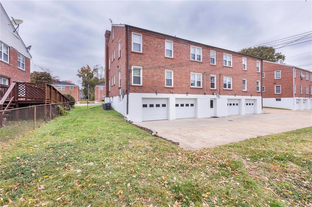 exterior space with central AC unit, a garage, and a yard