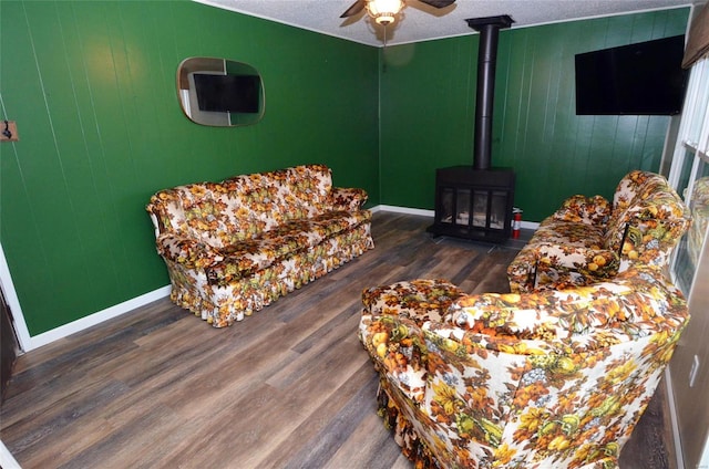 living room with a wood stove, dark hardwood / wood-style flooring, a textured ceiling, and ceiling fan