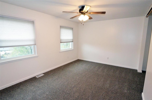 empty room featuring ceiling fan and dark carpet