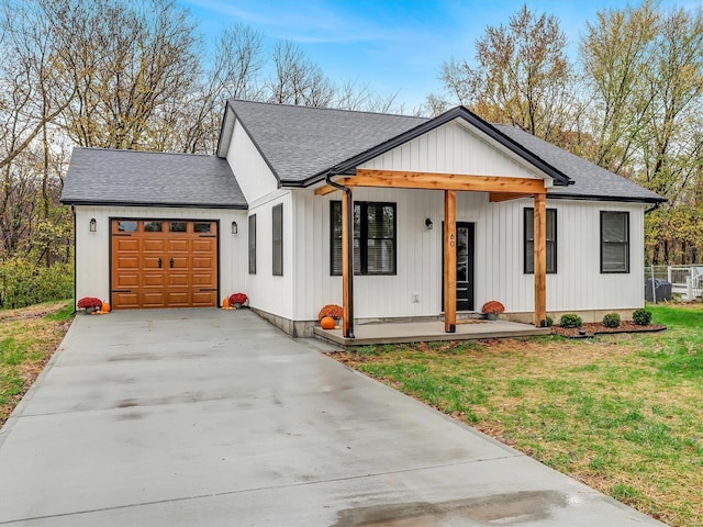 modern farmhouse style home featuring covered porch, a garage, and a front yard