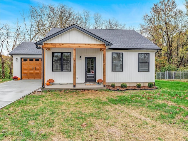 modern farmhouse featuring covered porch, a garage, and a front lawn