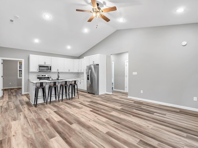 kitchen with a center island with sink, a kitchen breakfast bar, light wood-type flooring, and appliances with stainless steel finishes