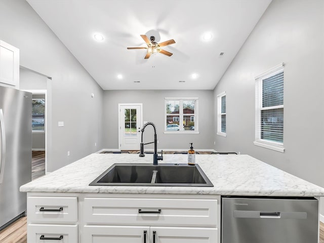 kitchen featuring white cabinetry, sink, stainless steel appliances, an island with sink, and vaulted ceiling