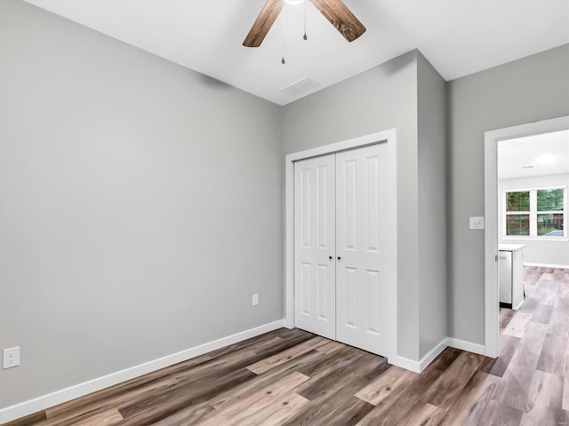 unfurnished bedroom with ceiling fan, a closet, and dark hardwood / wood-style floors