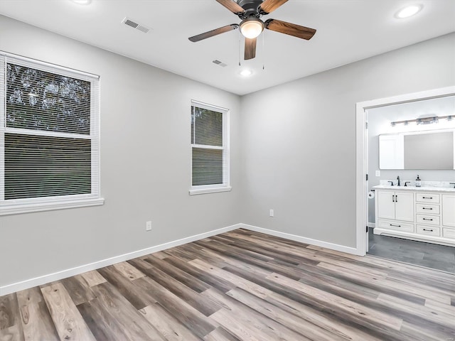 unfurnished bedroom featuring ceiling fan, light wood-type flooring, sink, and ensuite bath