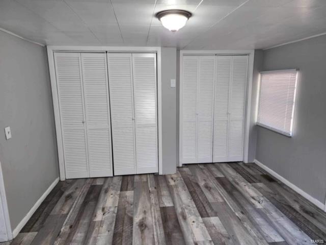 unfurnished bedroom featuring multiple closets and dark wood-type flooring