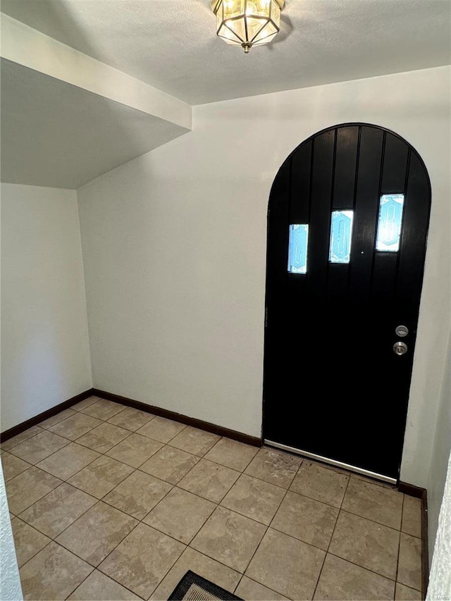 entryway with light tile patterned flooring and lofted ceiling with beams