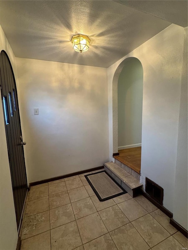 corridor featuring light tile patterned floors and a textured ceiling