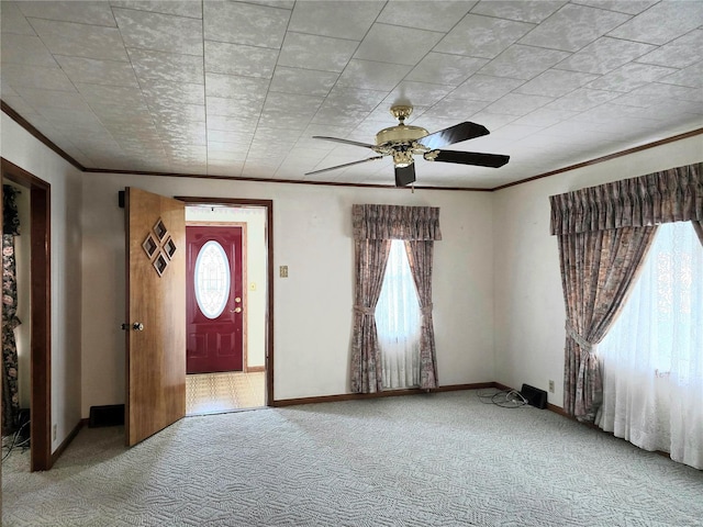 carpeted entrance foyer featuring ceiling fan and ornamental molding